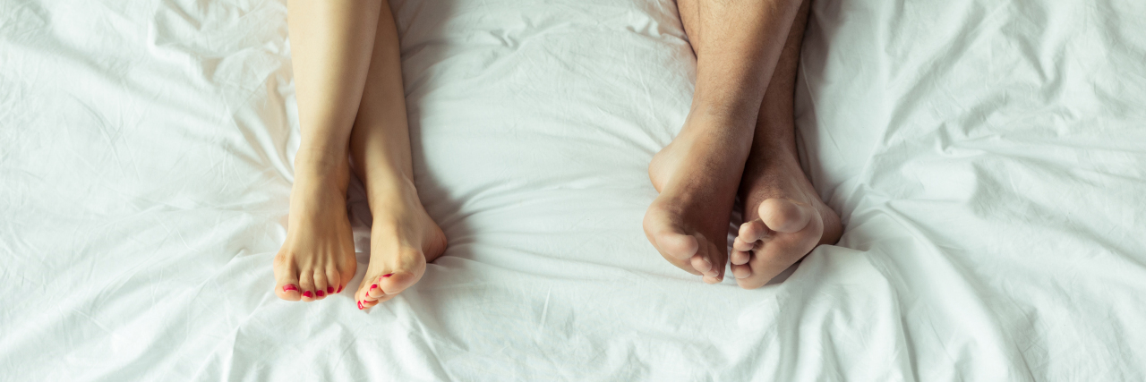 low section view of couple relaxing and lying on bed at home