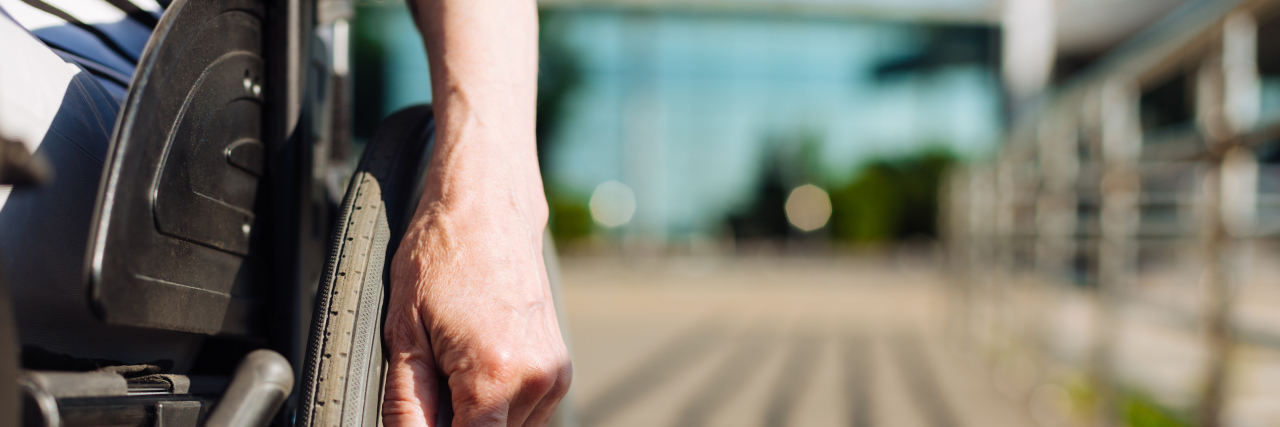 Disability and Lack of Privacy Woman pushing her wheelchair outside.