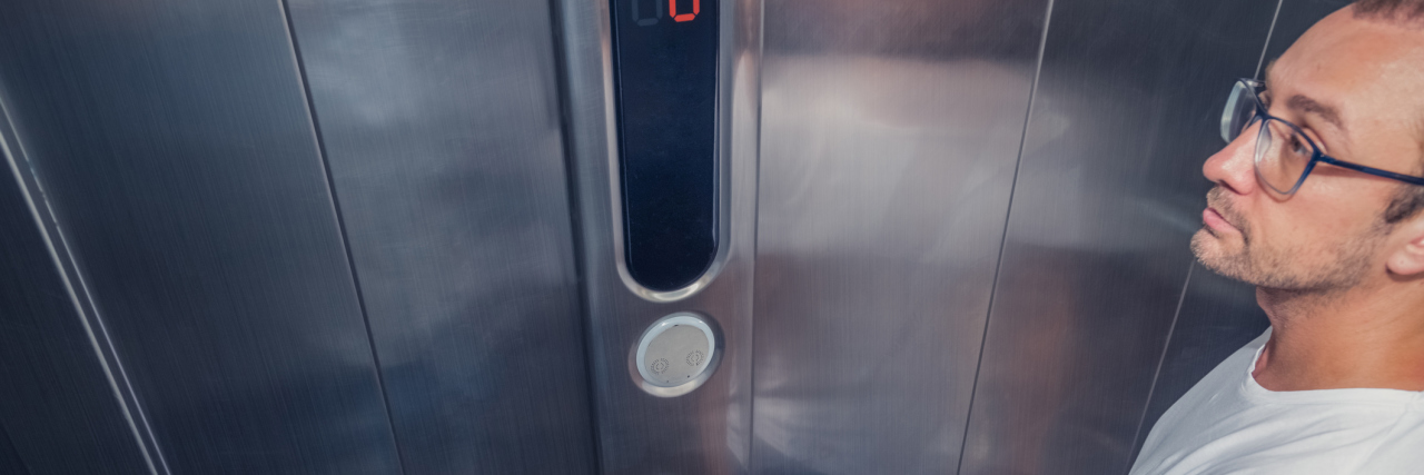 A man standing on an elevator pressing a button.