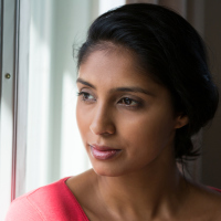 woman in a red shirt looking out through a window