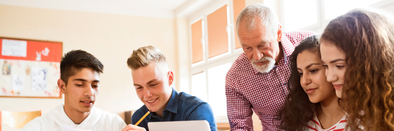 The Prominent Reason I Want to Go to School While Sick A teacher helping a group of students.