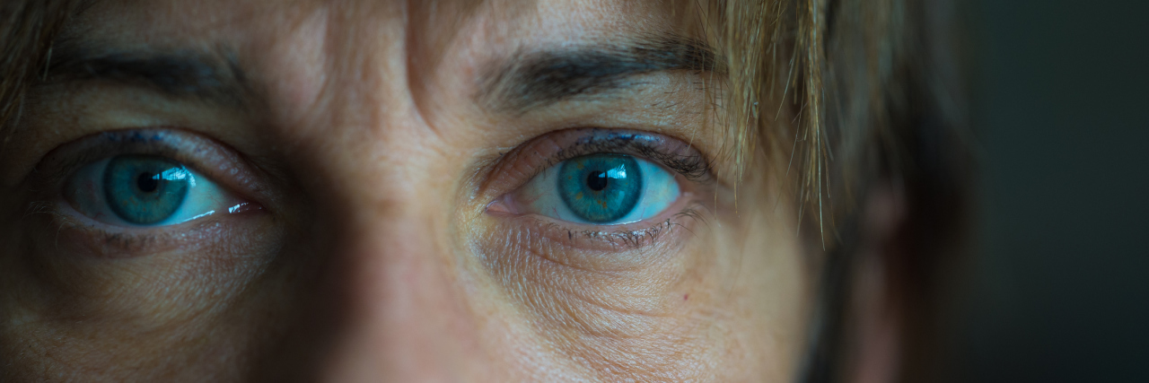 A middle-aged woman looking at the camera, with the photo being a close-up of her eyes.