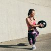 woman doing a stretching exercise outside with a medicine ball