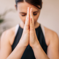 woman with her hands pressed together breathing and meditating