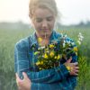 woman standing in a field holding flowers in her arms