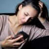 sad woman sitting at home and looking at her phone