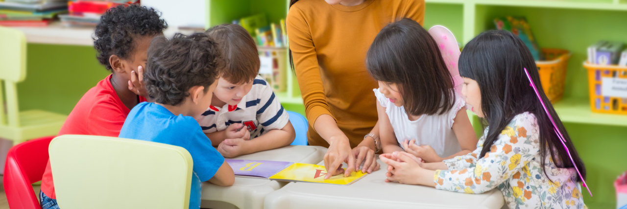 Lessons I Learned About Inclusion as My Son Finishes Kindergarten Asian female teacher teaching mixed race kids reading book in classroom,Kindergarten pre school concept