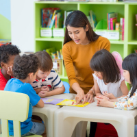 Asian female teacher teaching mixed race kids reading book in classroom,Kindergarten pre school concept