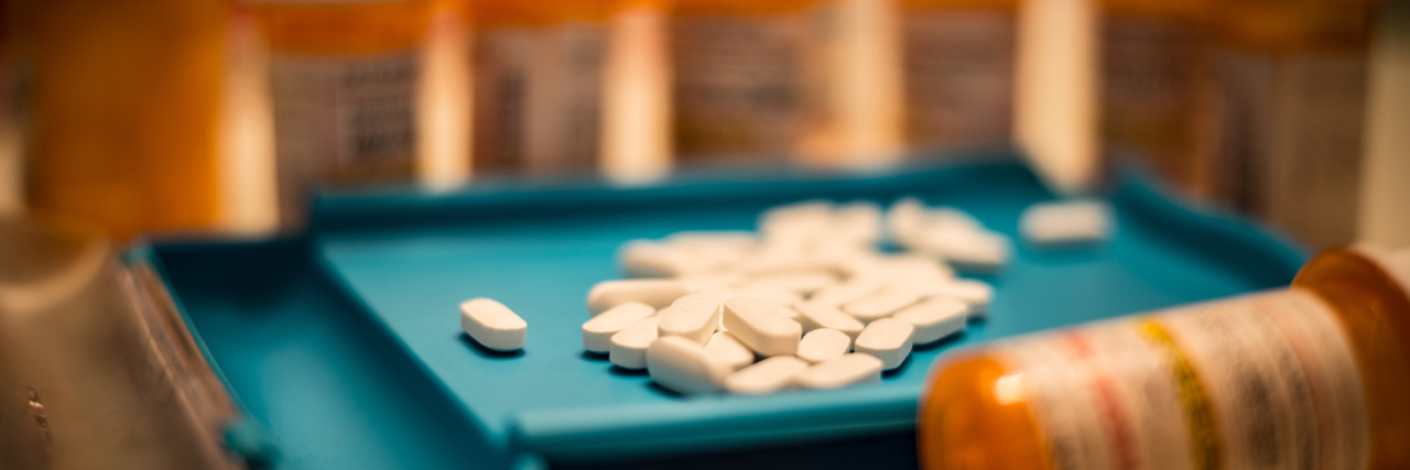 Unsorted prescription pills sit in a pharmacist's counting tray before they are bottled.