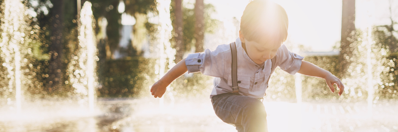 boy splashing around in fountain splashpad