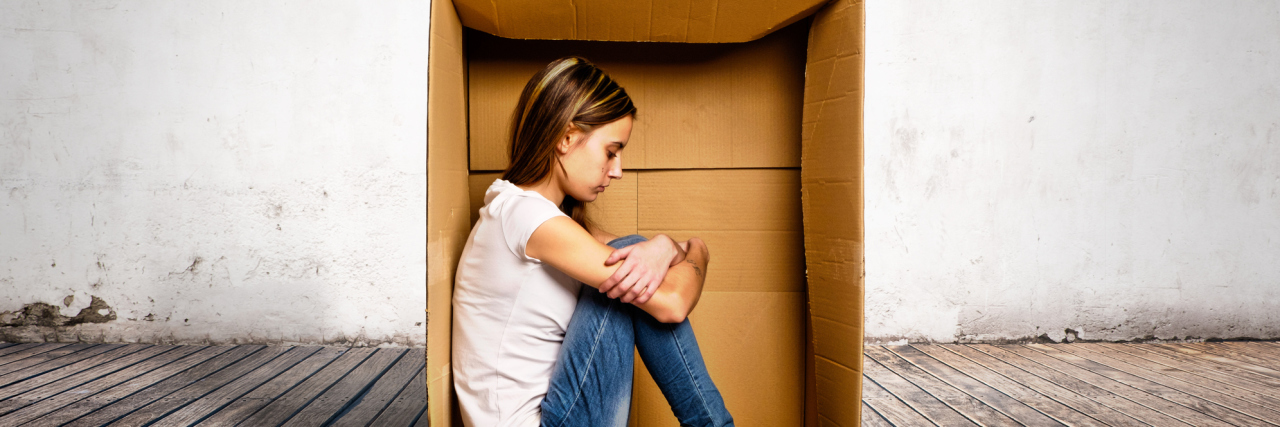 woman sitting inside a cardboard box