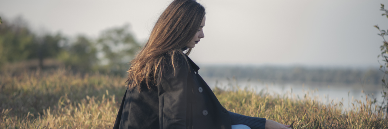 When Illness Makes You Give Up the Commitments and Activities You Love A sad woman sitting alone in a field of grass.