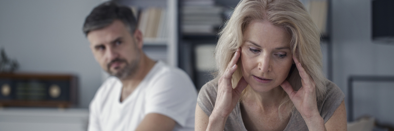 Study Finds Fighting With Spouse Leads to More Pain man and woman sitting on bed looking angry