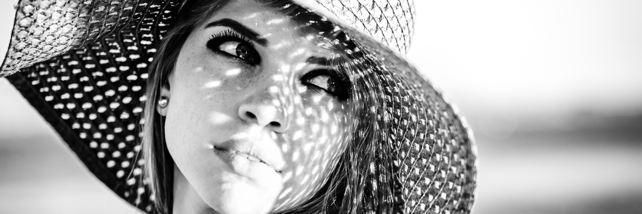 When We Think of Our Health Problems as 'Unfair' A black and white photograph of a woman wearing a sunhat.