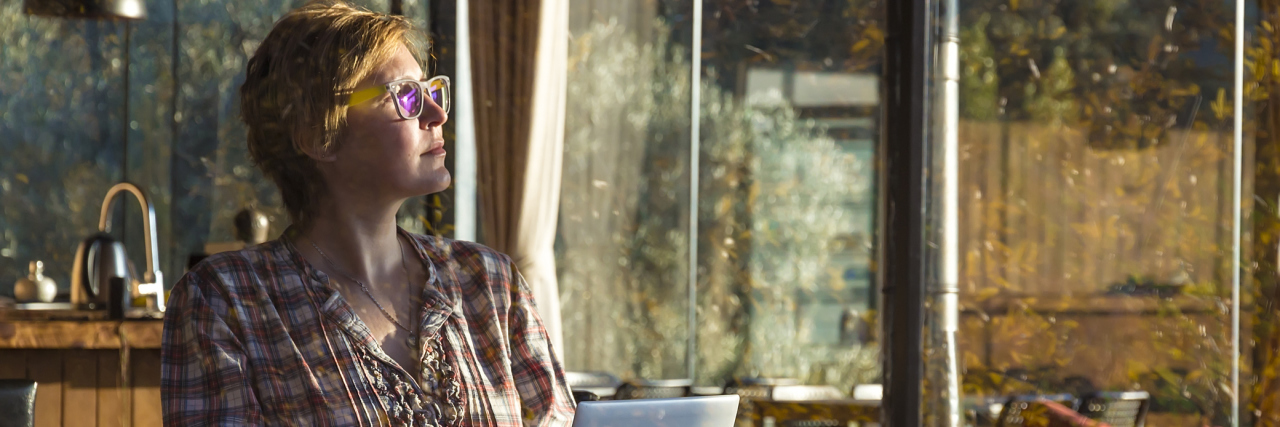 When MS Gives You Summertime Restrictions on Your Comings and Goings A picture of a woman sitting inside, on her computer.