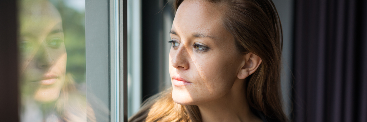 Why It's Difficult to Trust People as an Autistic Woman Woman looking at her reflection, deep in thought.