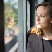 Woman looking at her reflection, deep in thought.
