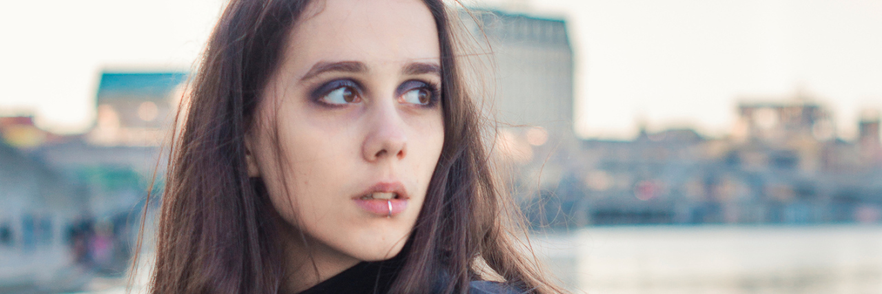 The 11 Years I Unknowingly Lived With Dysautonomia A woman standing outside, looking towards the left.