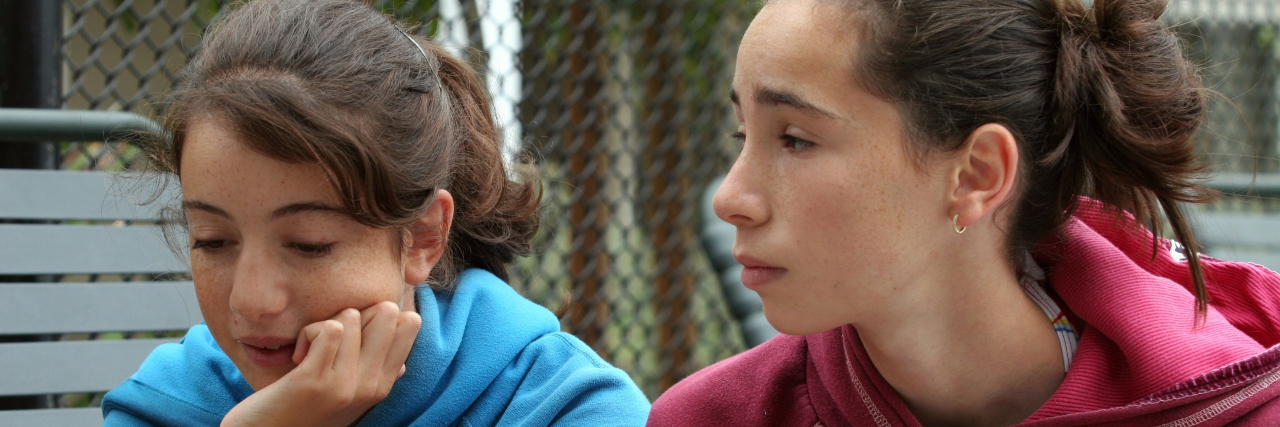 Why I Won't Compare My Pain to Others With Trigeminal Neuralgia two teen girls sitting next to each other