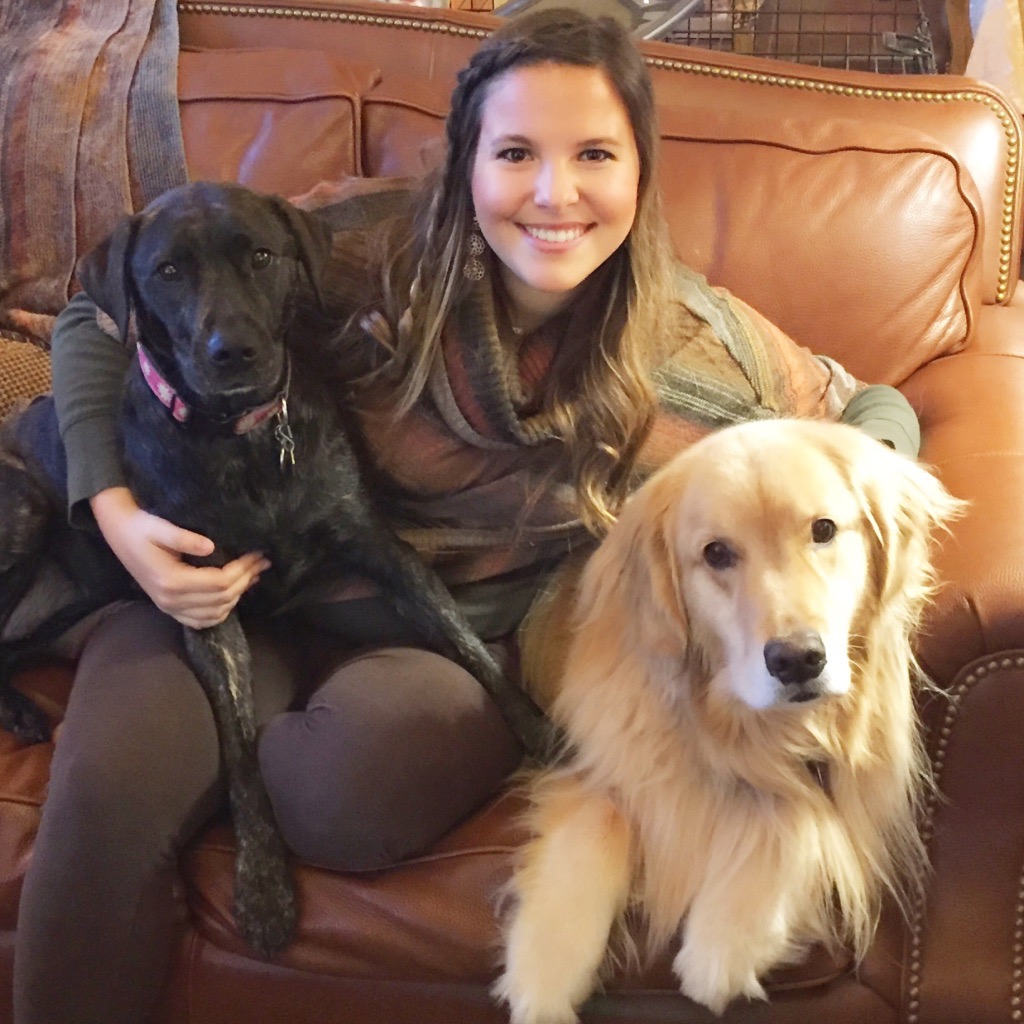 woman sitting on the couch smiling with two dogs