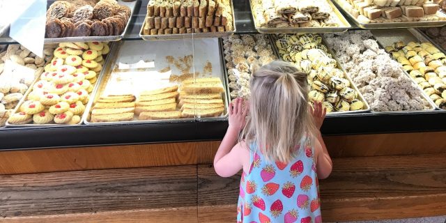 the author's daughter looking at cookies through the store window