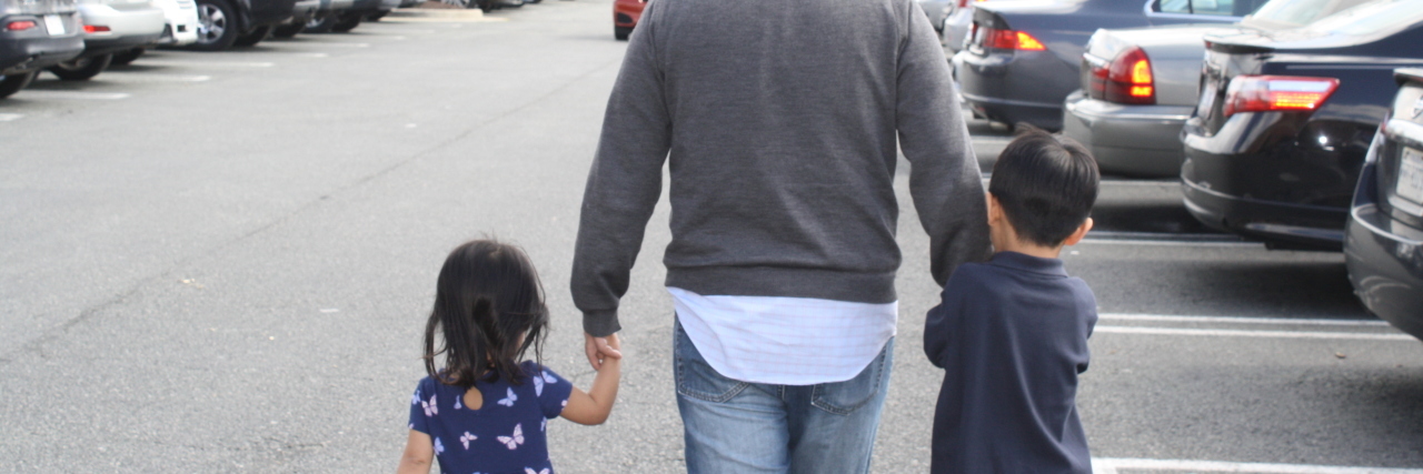 dad with his two kids in a parking lot