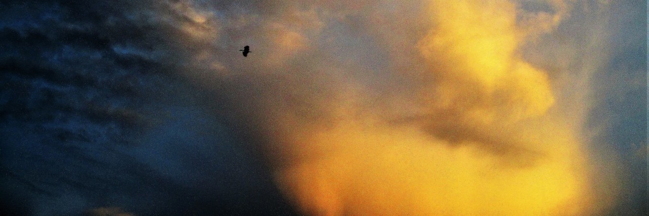 Chronic Illness Complicates My Answer to, 'What Do You Need?' A picture of the clouds in the sky, tinted with darkness and orange from a sunset or sunrise.