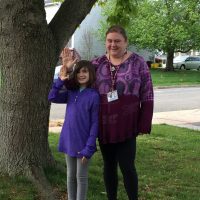 amanda and a child wearing purple shirts holding fingers in L shape