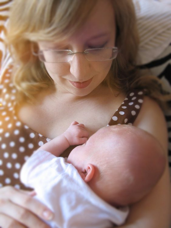 Mother holding baby in her arms while baby sleeps