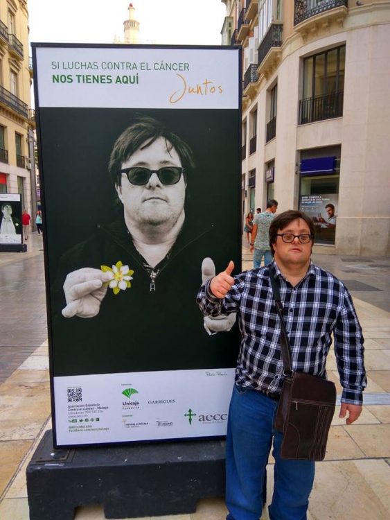 Pablo Pineda giving a thumbs up posing next to an advertisement featuring him (in Spain)