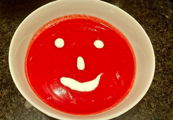 beet red soup with white smiley face of cream