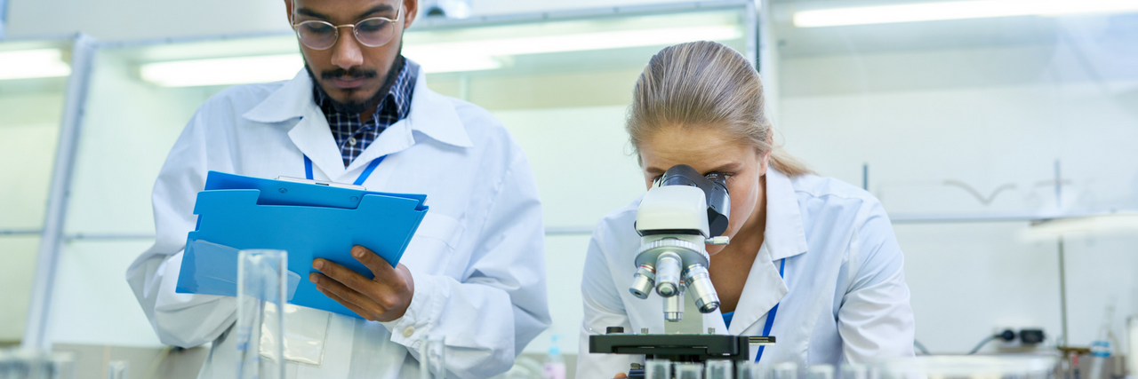 FDA Grants Fast Track Approval for Autism Drug Researchers in a lab with a microscope and test tubes.