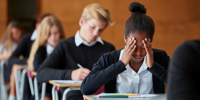 Black Children Are at a Higher Risk for Suicide Between the Ages of 5 and 12 A black female student sitting at a desk with her hands on her face.
