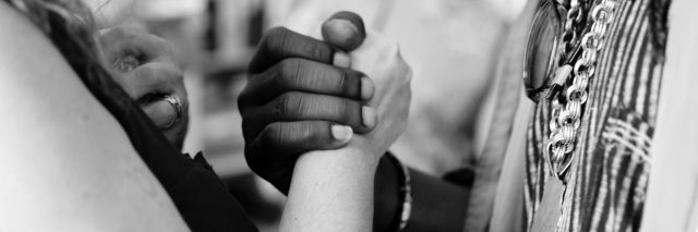 two people facing each other holding hands one person of color and one white person