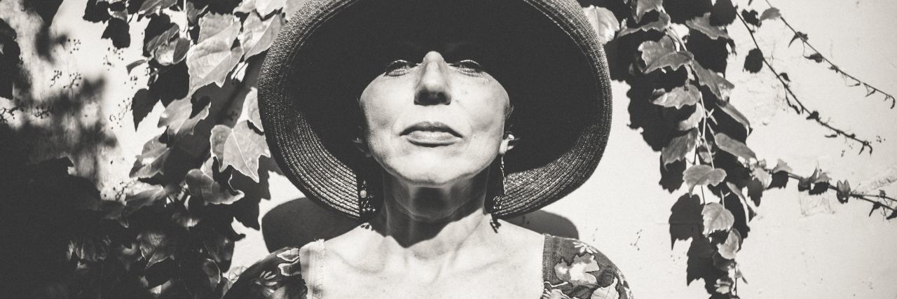 The Many Ways Chronic Illness Has Affected My Life black and white photo of woman standing against a wall with vines