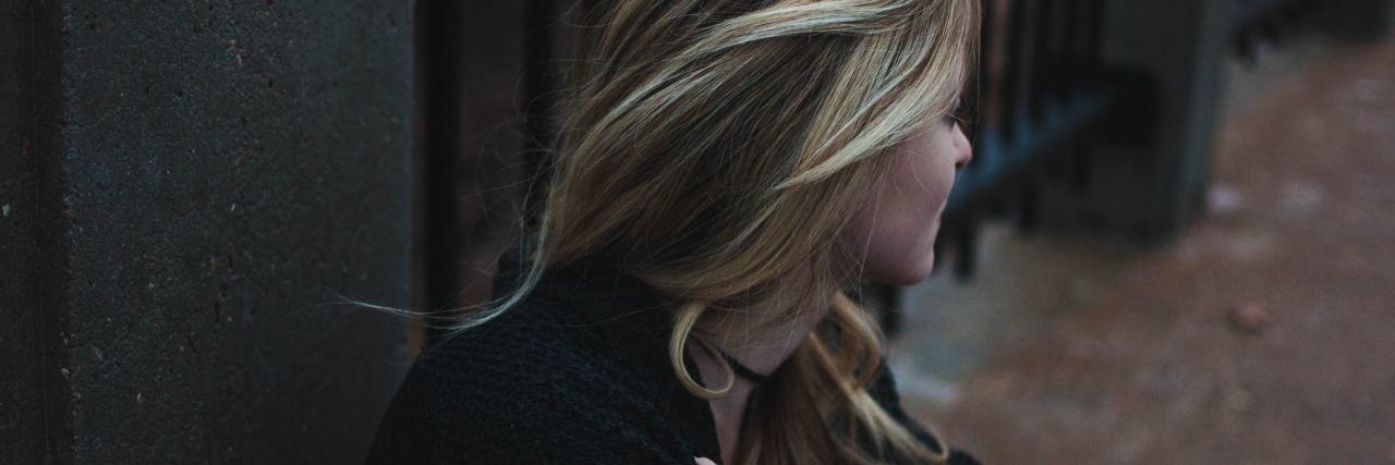 Persistent Depressive Disorder and ‘Double Depression' young blonde woman sitting on sidewalk with arms folded