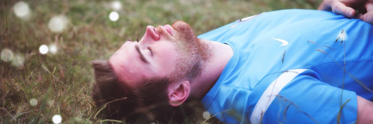 When OCD Affects You Only During Childhood man laying in field with lights dancing around him in the daytime