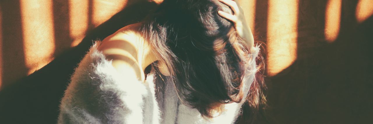 What to Do If Panic Attack Makes Me Afraid I'm Dying woman with hand in head looking down against sunlit wall