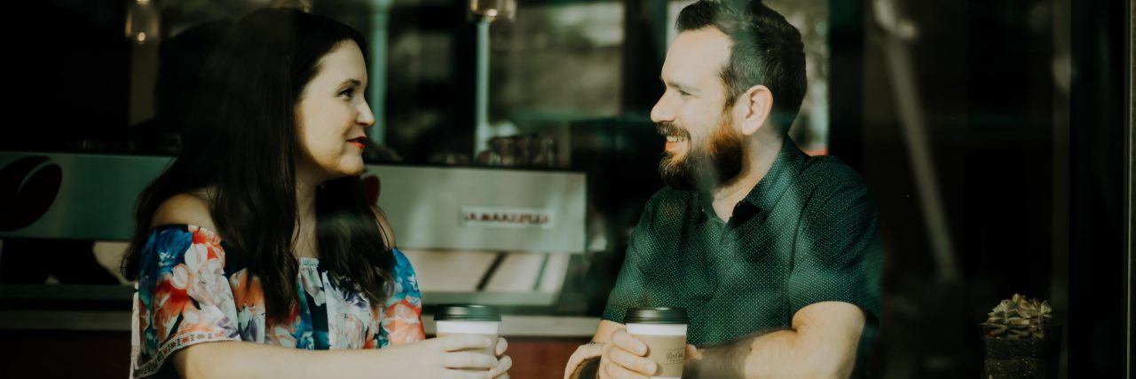 How to Fight Mental Health Stigma in Casual Conversation man and woman in coffee shop having conversation as seen from window looking in