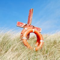 Cross and life preserver in a field.