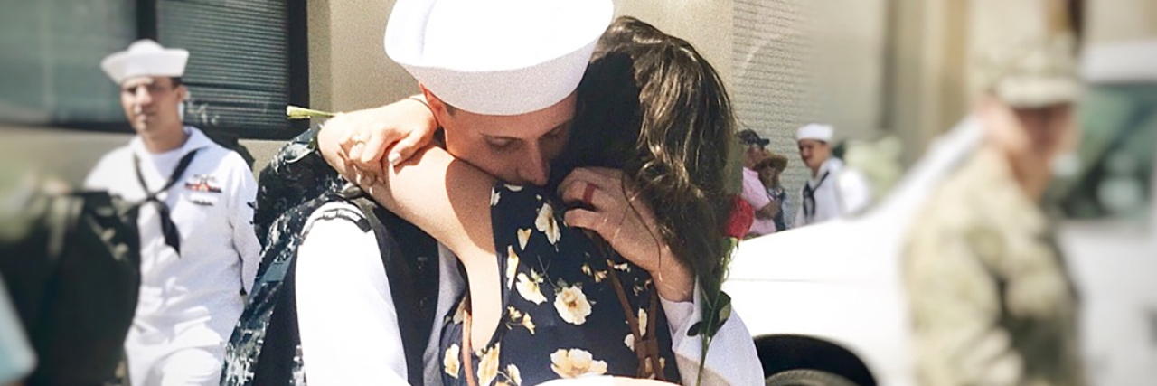 How to Cope as a Military Wife With Depression and Anxiety woman in flower dress and navy husband returning from deployment and embracing