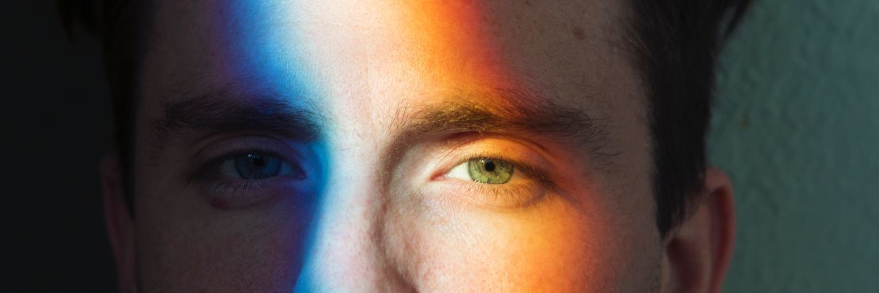 man with rainbow light shining across his face