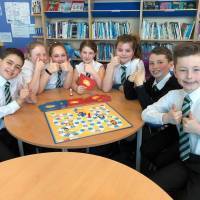 Group of kids giving thumbs up around a table with the game