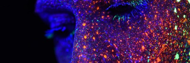 colorful photo of woman close up with multicolor lights superimposed on her face with her eyes closed