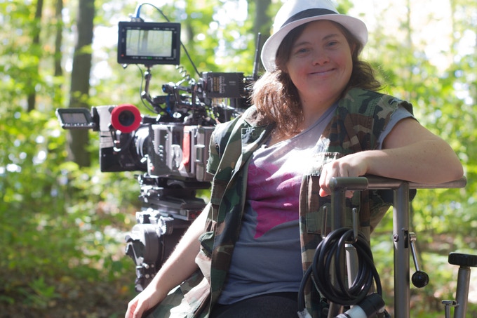 Marissa sitting at director's chair and smiling at camera with recording equipment behind her