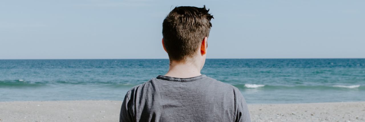 Why Depression and Sadness Are Not the Same Thing man on beach looking out to water and pale blue sky
