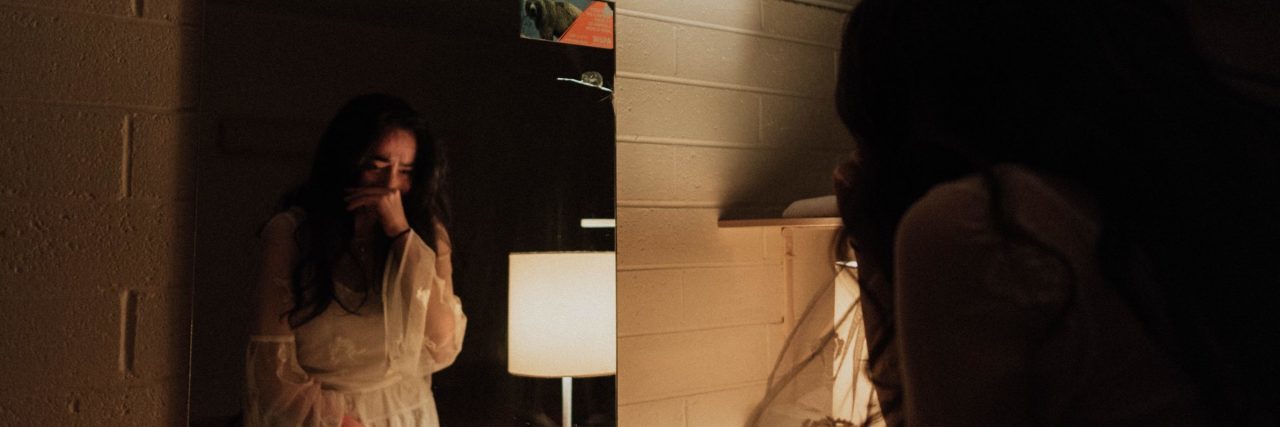 How and Why I Realized It’s Dangerous to Minimize Assault woman in bathroom looking at herself in mirror and crying