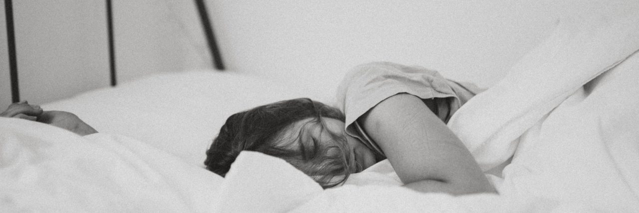 black and white photo of exhausted young woman in bed