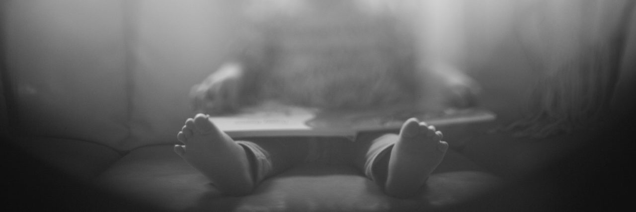 blurred photo of little girl reading book on couch