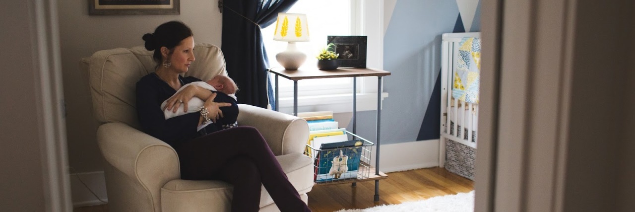 Life and Loss in the Down Syndrome Community Mother sitting on comfy chair in nursery holding her baby